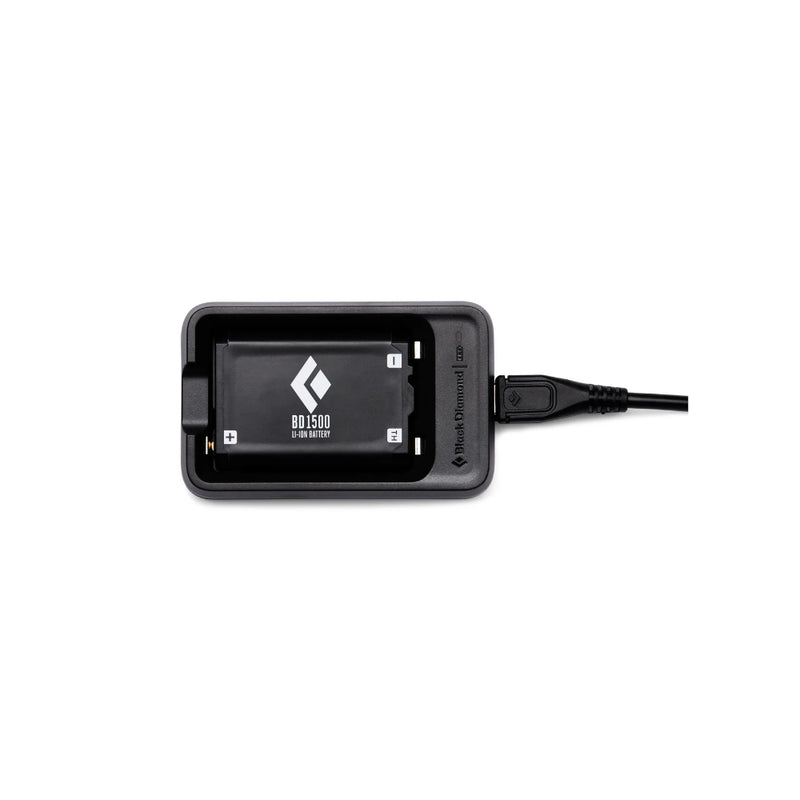 Black | Black Diamond BD 1500 Battery And Charger Image Showing Battery In Charging Cradle With Cord Plugged into Cradle.