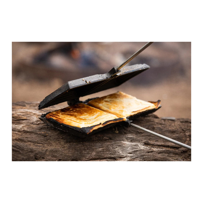 Black / Double | Campfire Double Jumbo Jaffle Iron Image Showing Iron Sitting On A Log Being Open After Cooking To Remove The Jaffles.