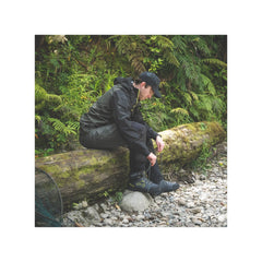 Slate | Desolve Rise Boots Image Showing Model Sitting On A Log To Lace Up Boots.