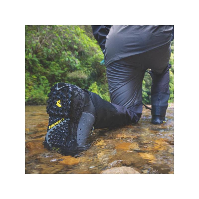 Slate | Desolve Rise Boots Image Showing Model Kneeling Down In A Stream, Tread Of Boots On  Display.