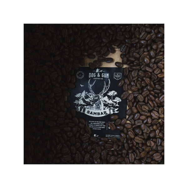 750g | Dog & Gun Sambar Dark Roast Whole Bean Coffee Image Showing The Logos Surrounded By The Coffee Beans.