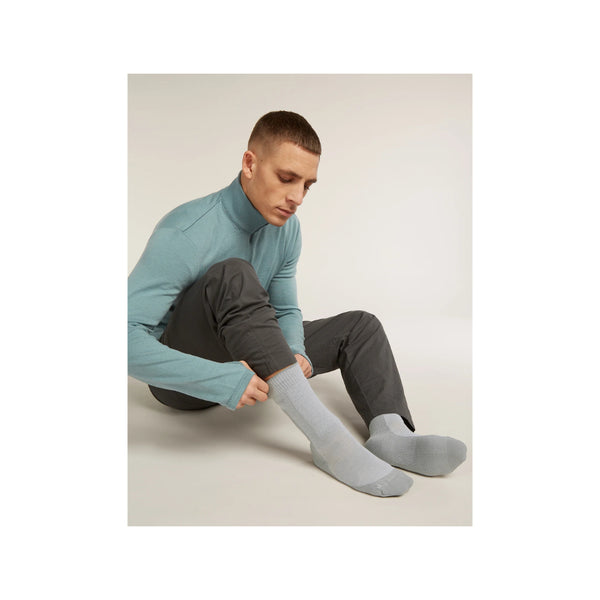 Grey | Icebreaker Men's Merino Hike + Heavy Crew Socks Image Showing Male Model Putting On The Crew Socks.