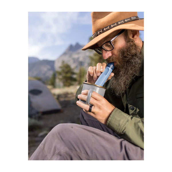 Mountain Blue | LifeStraw Peak Personal Water Filter Straw Image Showing Model Using The LifeStraw To Drink Out Of A Cup.