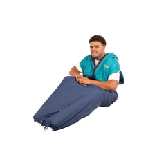 L/XL Blue | Oztrail Sleep Walker Sleeping Bag Image Sowing Model Sitting Down With The Bottom Of The Sleep Walker Sleeping Bag Close For Sleeping.