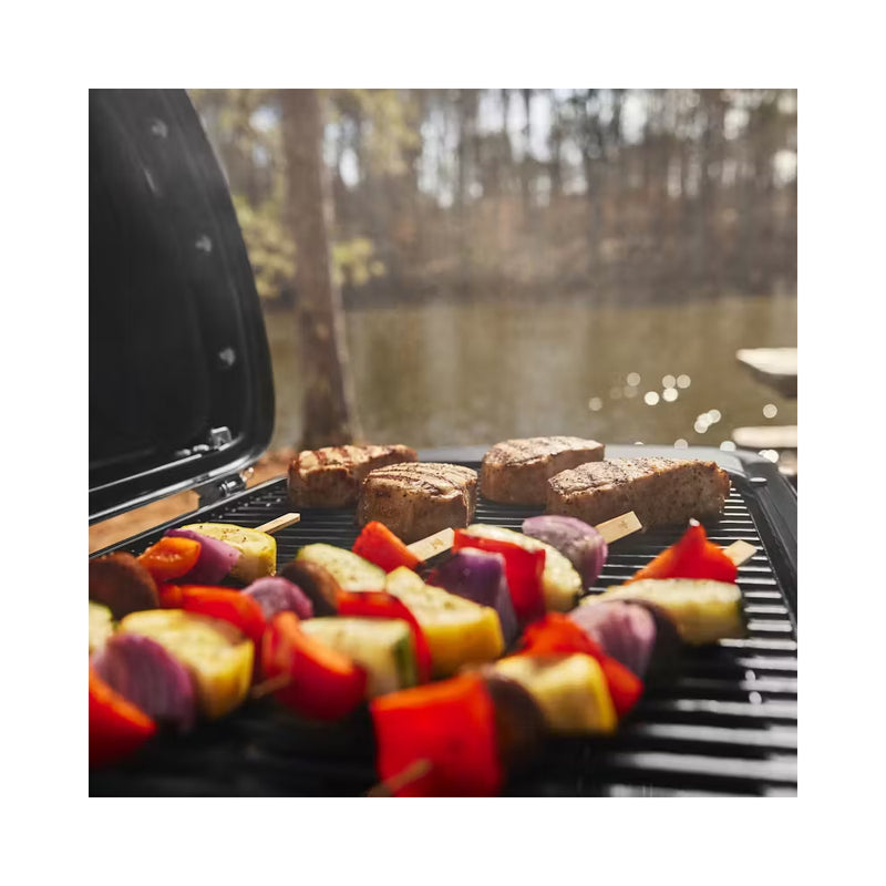 Black | Weber Traveler Compact Portable Gas BBQ Image Showing Angled View Of Grill Plate With Food Cooking.