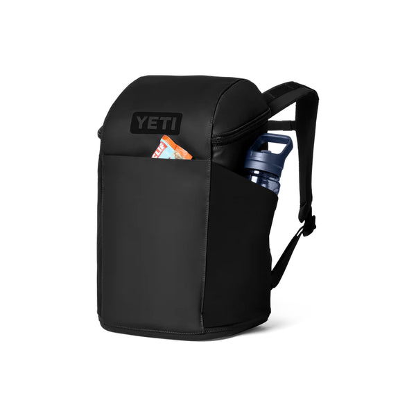Black | YETI Daytrip Insulated 20L Backpack Image Showing Angled Front View With Things In The Front And Side Pockets.