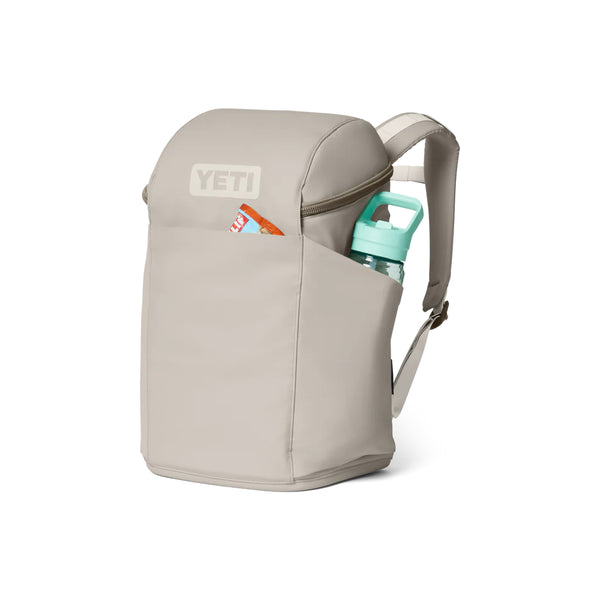 Cape Taupe |  YETI Daytrip Insulated 20L Backpack Image Showing Angled Front View With Things In The Front And Side Pocket.