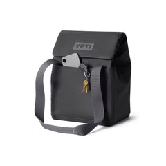 Charcoal / 14L | YETI Daytrip Insulated Tote Bag Image Showing Angled Front View, Closed , Front MAGSNAP Pocket Being Used To Hold A Phone And Keys, Handles Down.