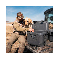 Charcoal | YETI Roadie 15 Hard Cooler Image Showing The cooler On The Back Of A Ute Tray With A model And His Dog, Removing A Drink From The Cooler.