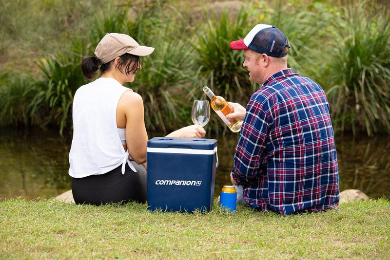 Blue and White | Companion Hard Cooler 14L. Lifestyle image of couple next to creek with cooler and wine