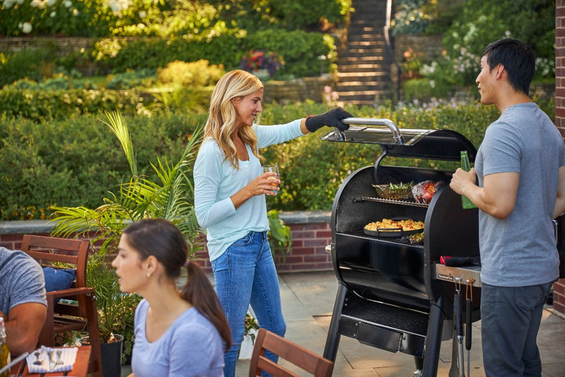 People viewing the contents of the smoker while entertaining guests.