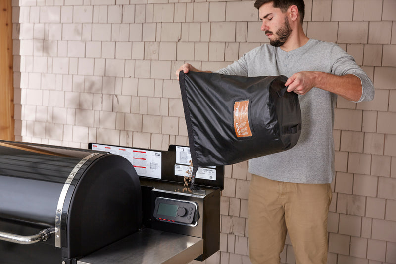 Pouring Pellets into Smoke Fire Pellet Hopper from Bag Showing handles on the bottom of the bag for easy grip