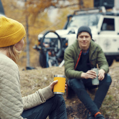 Glow | Image of 2 people sitting near a car holding a glow and moss tumbler